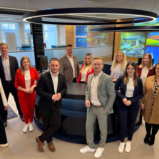 Eine Gruppe von Menschen posiert fur ein Foto in einem Buro. Das Buro hat ein modernes Design.