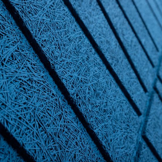Eine Nahaufnahme einer blauen strukturierten Oberfläche mit dünnen, wellenförmigen Linien, die vertikal verlaufen. Die Textur ist faserig und erscheint gefroren.