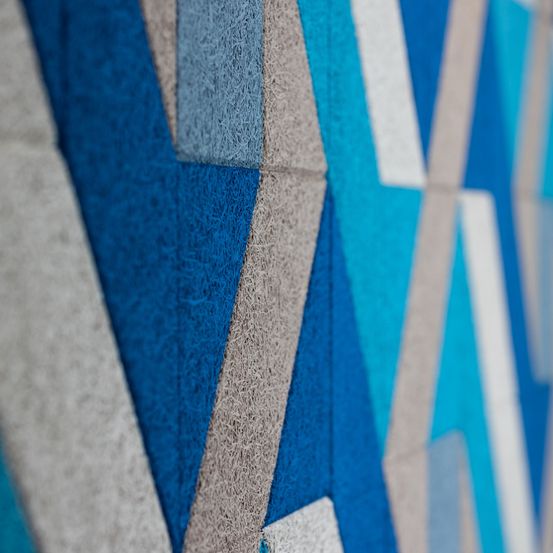 Eine Nahaufnahme eines modernen geometrischen Wanddesigns mit blauen und grauen Farben, das eckige Formen und strukturierte Oberflächen aufweist.