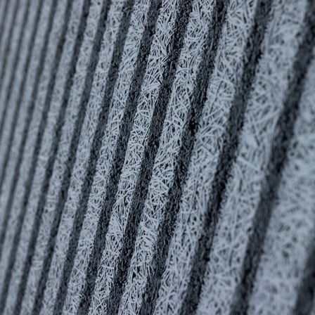 Eine Nahaufnahme einer strukturierten Oberfläche mit vertikalen Linien, die mit Frost bedeckt sind. Das Muster ist wiederholt, mit abwechselnden dunklen und hellen Bereichen.