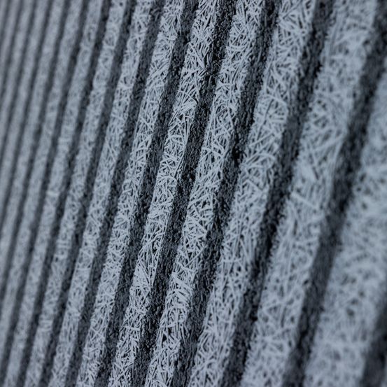 Eine Nahaufnahme einer strukturierten Oberfläche mit vertikalen Linien, die mit Frost bedeckt sind. Das Muster ist wiederholt, mit abwechselnden dunklen und hellen Bereichen.