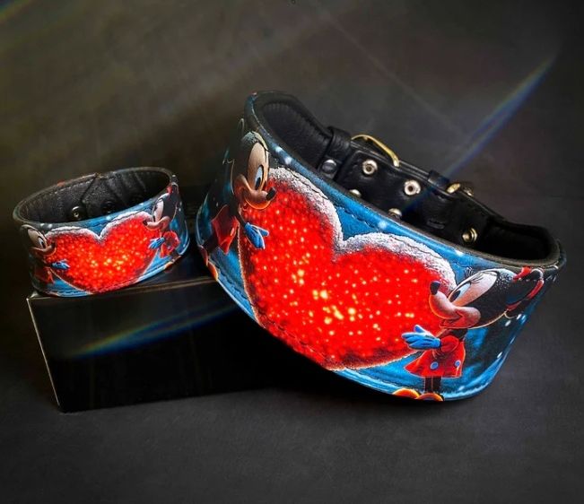 Zwei Mickey-Mouse-Halsbänder mit leuchtendem Herzdesign, eines in Blau und eines in Rot, auf schwarzem Hintergrund präsentiert.