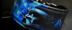 Ein blauer und schwarzer Lederhalsband mit einem Darth Vader-Maskendesign vor einem dunklen Weltraumhintergrund.