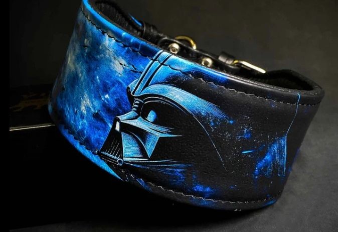 Ein blauer und schwarzer Lederhalsband mit einem Darth Vader-Maskendesign vor einem dunklen Weltraumhintergrund.