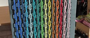 Eine Ausstellung von farbenfrohen Kettenleinen für Haustiere, aufgehängt an einer Metallwand mit Haken, neben verschiedenen Hundehalsbändern und Spielzeug.