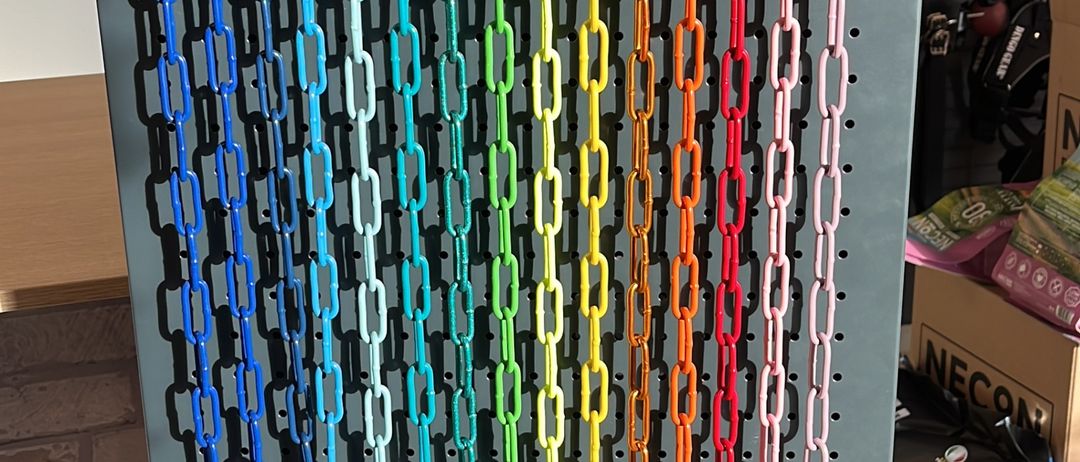 Eine Ausstellung von farbenfrohen Kettenleinen für Haustiere, aufgehängt an einer Metallwand mit Haken, neben verschiedenen Hundehalsbändern und Spielzeug.