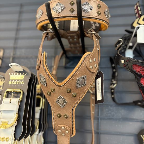 Ein braunes Lederhalsband für Hunde mit dekorativen Nieten und Reißverschlüssen wird auf einem Metallregal mit anderen Produkten ausgestellt.