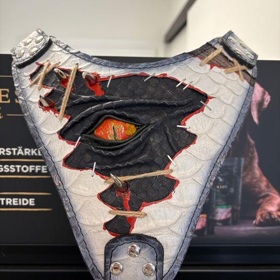 Eine Ledermaske mit Augendesign, in Rot-Schwarz gehalten, mit einem roten Auge in der Mitte.