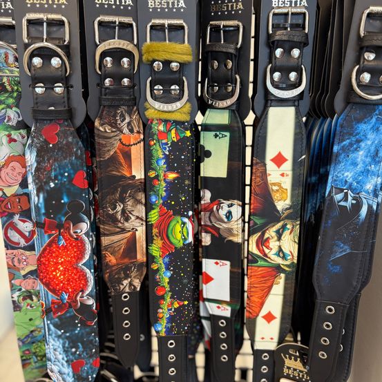 Eine Reihe von Ledergurten mit verschiedenen Designs wie Mickey Mouse, Batman und Spielkarten, die auf einem Ständer ausgestellt sind.