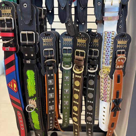 Eine Auswahl verschiedener Ledergürtel mit einzigartigen Designs und Farben, einschließlich eines Superman-Themengurts, wird auf einem Ständer präsentiert.