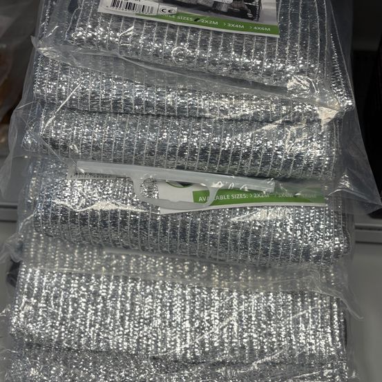 Mehrere Packungen mit silbernen Glitzerstoffrollen in Plastik, mit Größen beschriftet.