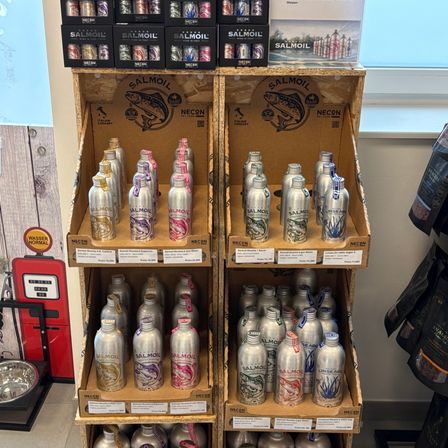 Eine Ausstellung von Getränkedosen, hauptsächlich Salmon Dosengetränke, in mehreren Schichten angeordnet mit Etiketten und Fischdesign.