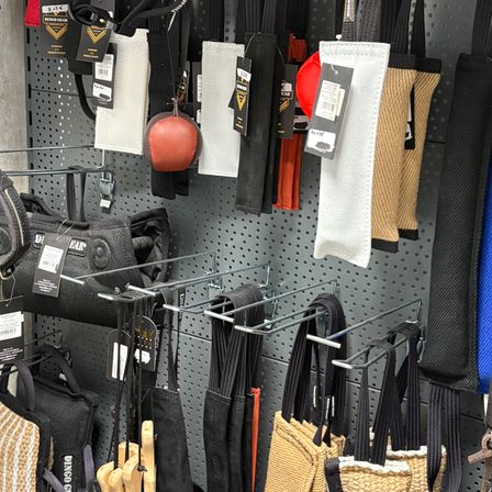 Ein wandmontiertes Display zeigt verschiedene Fitness-Zubehörteile, darunter schwarze und beige Taschen, rote und weiße Polsterung sowie einen roten Medizinball.