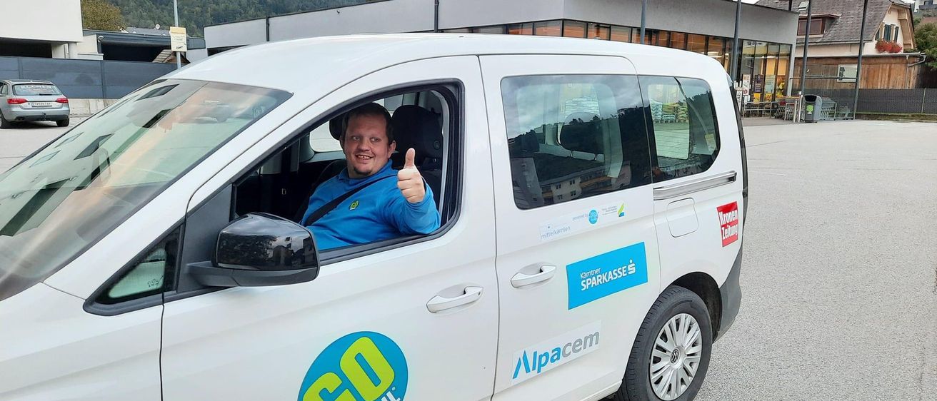 Ein Mann sitzt in einem weissen GO MOBIL-Van auf einem Parkplatz vor einem BILLA-Geschäft.