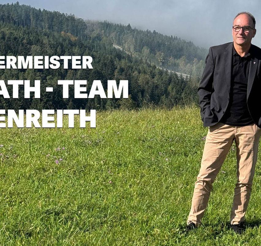 Ein Mann steht auf einem Feld mit grünem Gras, trägt eine Brille und einen schwarzen Anzug und lächelt in die Kamera. Der Hintergrund zeigt einen Wald und eine Straße mit einem Zug. Die Überlagerungstexte lauten 'ERMEISTER ATH-TEAM ENREITH'.