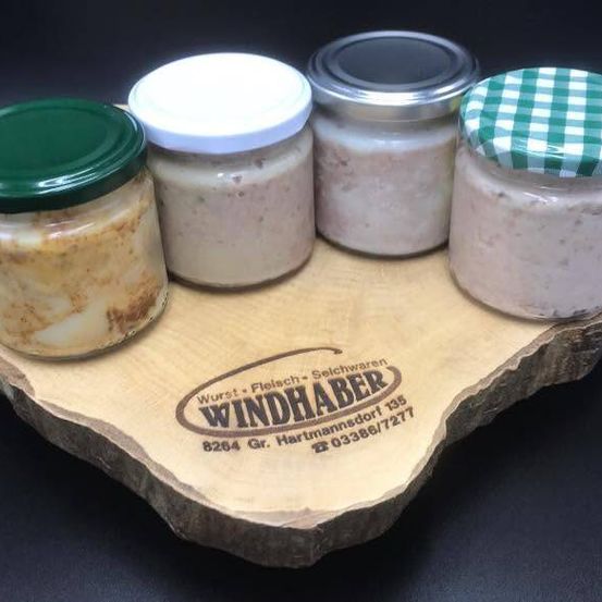 Four jars of different contents on a wooden board with a brand logo. The jars have different colored lids.