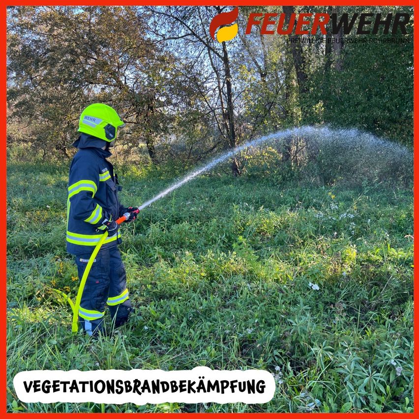 Ein Feuerwehrmann sprüht Wasser in einem Grasfeld mit Bäumen. Er trägt einen grünen Helm und eine Uniform. Das Bild hat einen roten Rand und die Worte 'Vegetationsbrandbekampfung' unten.