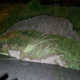 Ein nächtlicher Blick auf einen Grashügel mit einem Erdhügel neben einer asphaltierten Straße.