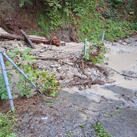 Ein überschwemmtes Gebiet mit schlammigem Wasser, verstreutem Schutt und einigen Metallpfosten an der Seite.