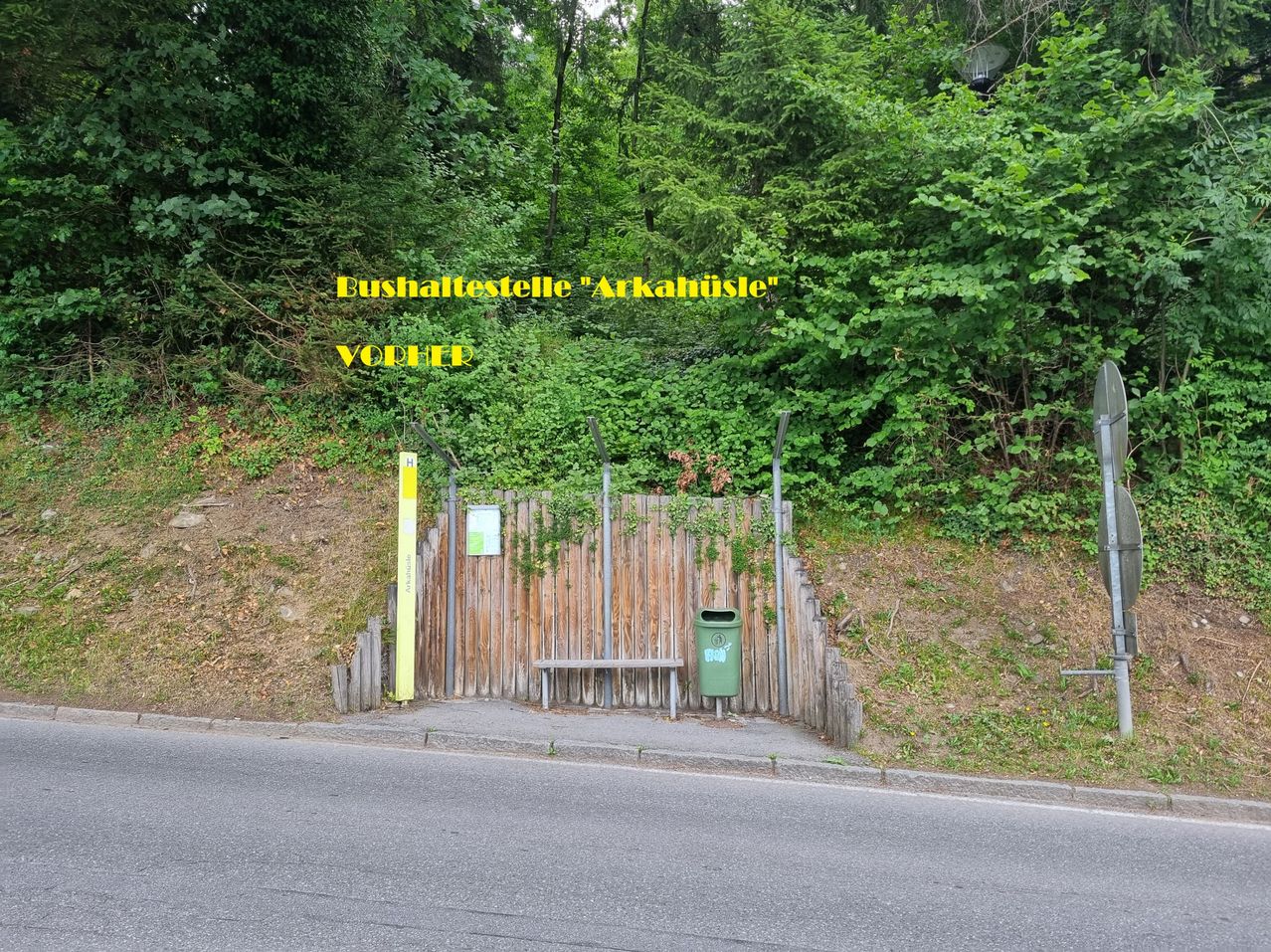 Eine kleine Bushaltestelle namens 'Arkahüsle' ist von Grün umgeben. Eine Bank und ein Mülleimer sind vorhanden. Ein Schild auf der linken Seite steht 'Vorher'.