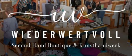 A second-hand boutique with various items on display. Many people are browsing. There are plants, handbags, and a table with many items.