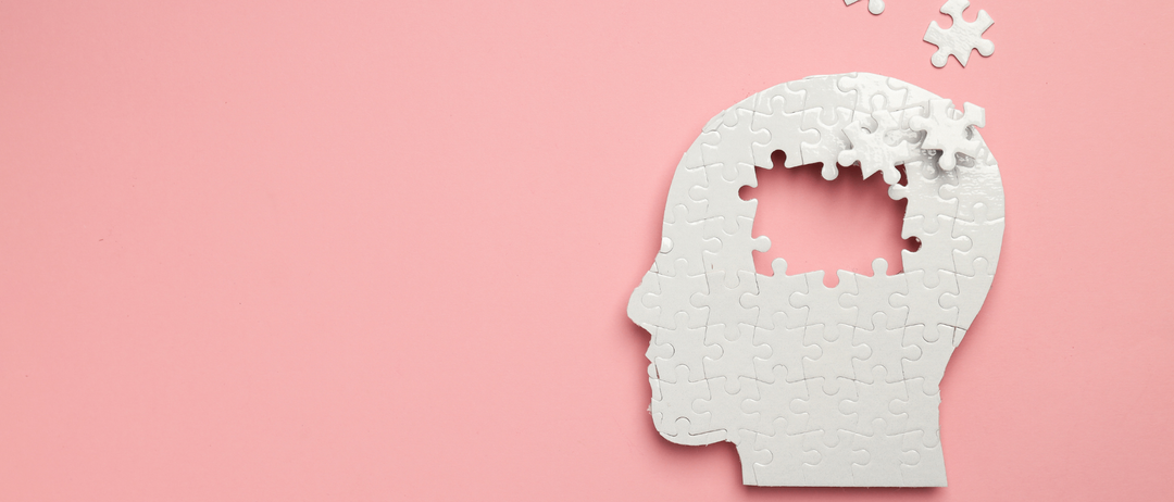 Ein weißer Puzzleteilkopf auf einem rosa Hintergrund mit anderen Puzzleteilen, die darüber schweben.