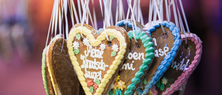 Herzförmige Kekse mit deutschem Text hängen an Schnüren. Verschiedene Farben und Designs sind sichtbar.