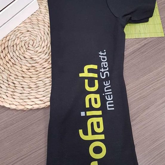 Ein schwarzes T-Shirt mit dem Wort 'Rofalch' in Gelb und Weiß auf der Vorderseite und 'Meine Stadt' in Weiß an der Seite.