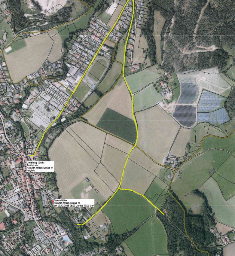 Luftaufnahme eines Gebiets mit Wohn-, Industrie- und Landwirtschaftszonen. Eine gelbe Linie markiert eine Grenze. Gebäude und Straßen sind sichtbar. Das Gebiet umfasst ein Feld, ein Solarkraftwerk und eine Kleinstadt.