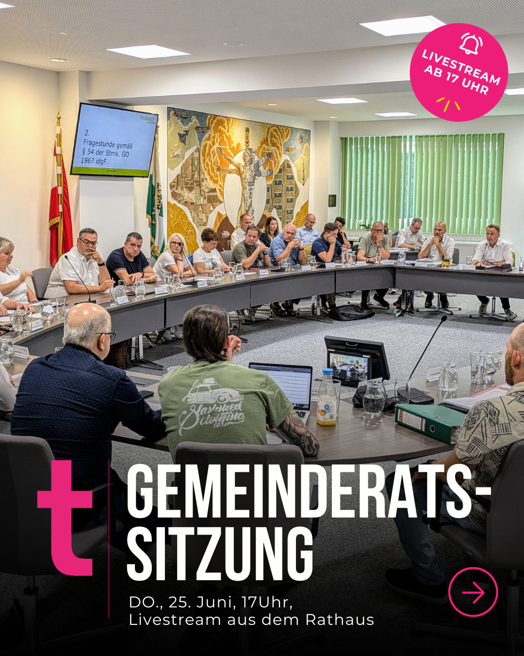 Eine Gruppe von Menschen sitzt um einen Tisch herum in einer Besprechung. Ein Bildschirm zeigt eine Präsentation mit Fragen und Antworten. Die Besprechung handelt von Gemeindethemen.