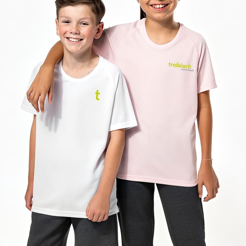 Two kids are standing close to each other, both smiling. The boy is wearing a white t-shirt with a yellow t logo. The girl is wearing a pink t-shirt with the text TROFAIACH.
