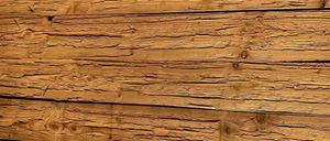 Eine Nahaufnahme von Holzbrettern mit sichtbaren Ästen und Maserungen. Das Holz hat einen verwitterten, rustikalen Look.