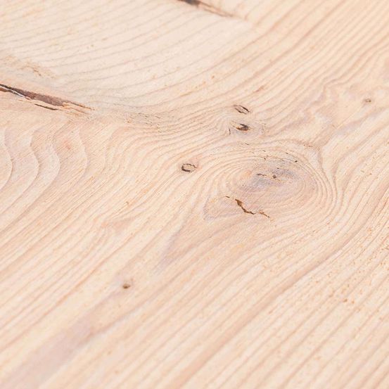 Eine Nahaufnahme einer hellen Holzoberfläche mit sichtbaren Maserungen und Ästen, die die natürliche Textur des Holzes zeigt.