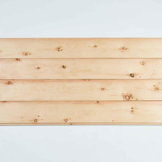 Eine Nahaufnahme einer Holzplatte vor weißem Hintergrund. Die Maserung des Holzes ist sichtbar mit mehreren Ästen und Unvollkommenheiten.