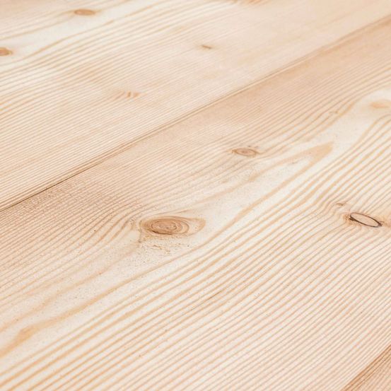 Eine Nahaufnahme eines Holzbodens mit natürlichem Maserungsmuster und einigen Astlöchern. Die Oberfläche ist glatt mit einer hellbeigen Farbe und zeigt die Textur des Holzes.