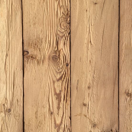 Ein Nahaufnahme von verwitterten Holzbrettern mit sichtbaren Holzmaserungen, Ästen und einer natürlichen goldbraunen Farbe. Das Holz wirkt gealtert mit einigen Abnutzungserscheinungen.