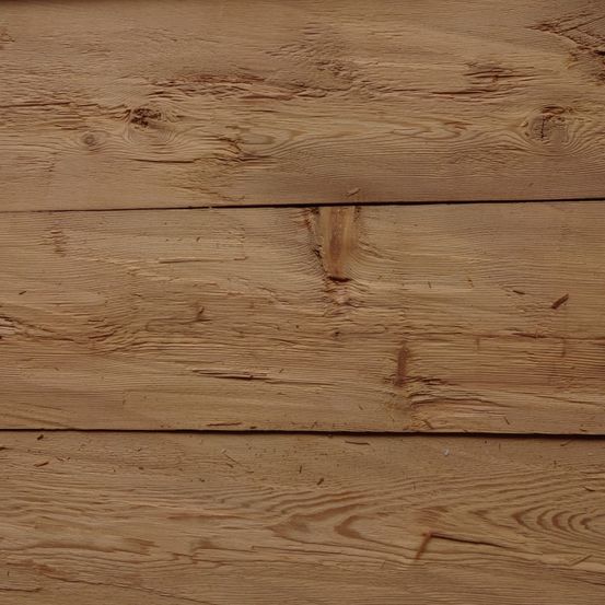 Eine Nahaufnahme von Holzbrettern mit sichtbaren Maserungen und einigen Unvollkommenheiten, einschließlich Ästen und Flecken.