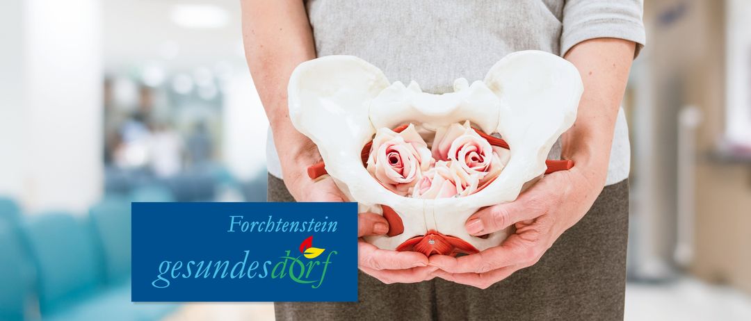 Eine Person hält ein Modell des menschlichen Beckens mit Rosen darin. Unten links befindet sich ein Logo.