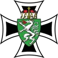 Ein heraldisches Emblem mit einem schwarzen Kreuz und einem weißen Wolfswappen, das einen rotzüngelnden Wolf auf einem grünen Schild mit einem Kreuz auf der Oberseite zeigt, vor schwarzem Hintergrund.