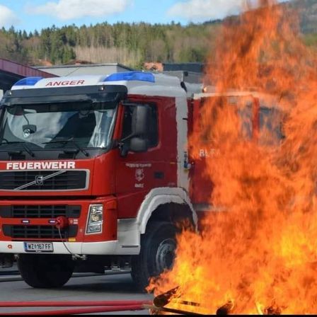 Ein roter Feuerwehrwagen mit der Aufschrift 'Feuerwehr', einem Hydranten und Flammen im Vordergrund.
