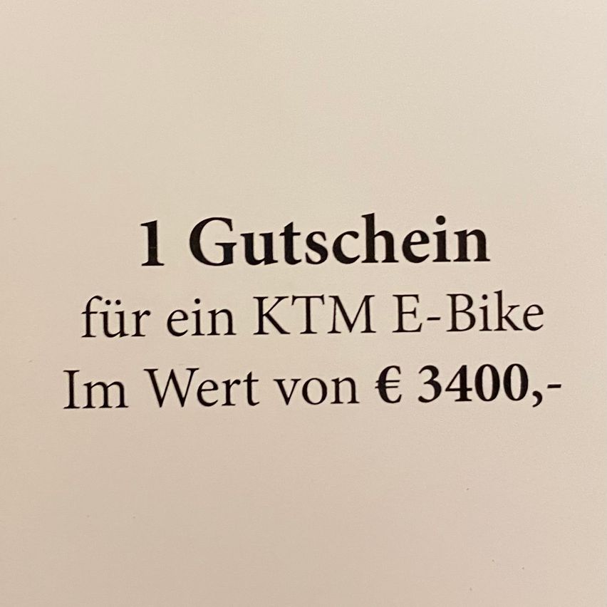Ein weißer Hintergrund mit schwarzem Text: '1 Gutschein für ein KTM E-Bike Im Wert von € 3400,-'. Der Text bedeutet '1 Gutschein für ein KTM E-Bike im Wert von 3400 €,-'.