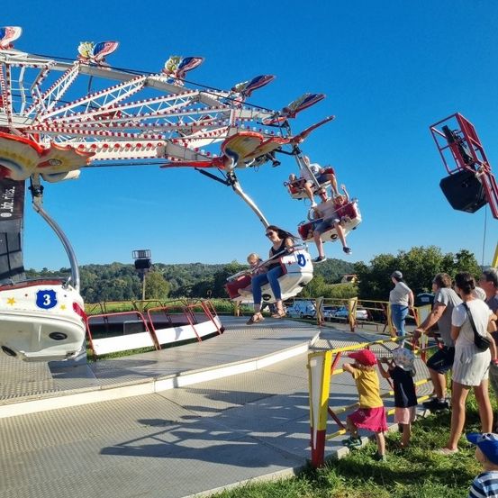 Eine Familie an einem sonnigen Tag wartet auf eine Fahrt mit einer bunten Schaukel-Achterbahn im Vergnügungspark.
