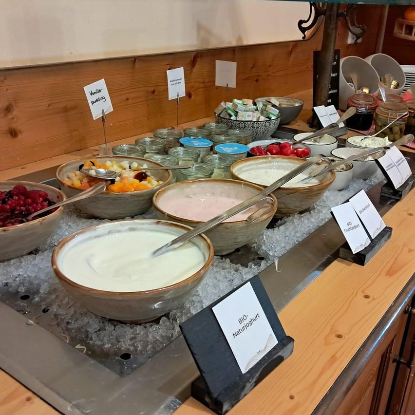 A buffet table with various bowls of yogurt, fruit salad, and other desserts, all labeled and placed on ice.
