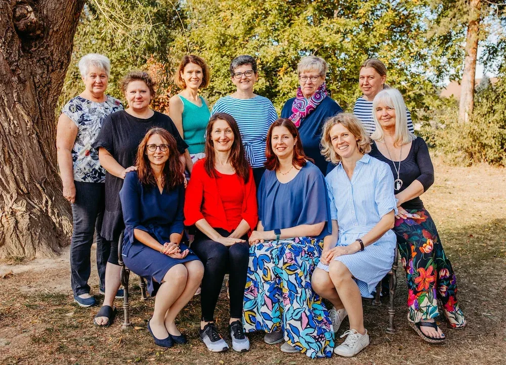 Eine Gruppe von Frauen, einige sitzend und einige stehend, posiert für ein Foto im Park.
