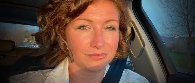 Eine Frau im Auto mit einer weißen Jacke, lächelnd, mit dem Thermomix Vorarlberg Logo auf ihrer Jacke.