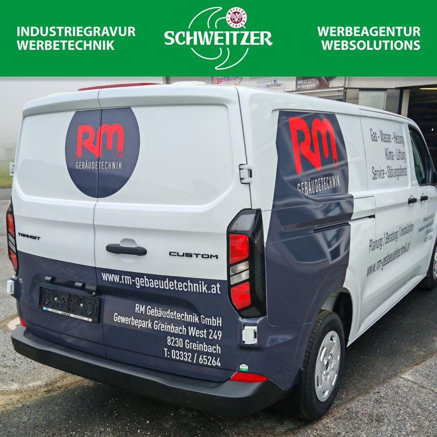 Die Rückseite eines weißen Lieferwagens mit blauen Aufklebern und der Aufschrift 'RM Gebaudtechnik', geparkt auf einem Parkplatz.