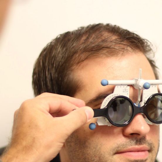 Ein Mann hält eine Brille mit Ophthalmoskop an sein Gesicht und überprüft seine Augen.