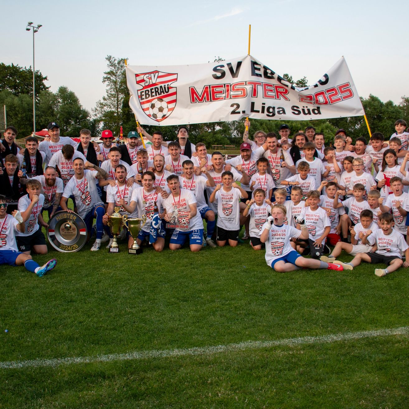 Eine Gruppe von Fußballspielern und Offiziellen posiert für ein Foto auf einem Feld mit einem Banner, das SV Eberau Meister 2024/25 2. Liga Süd liest.