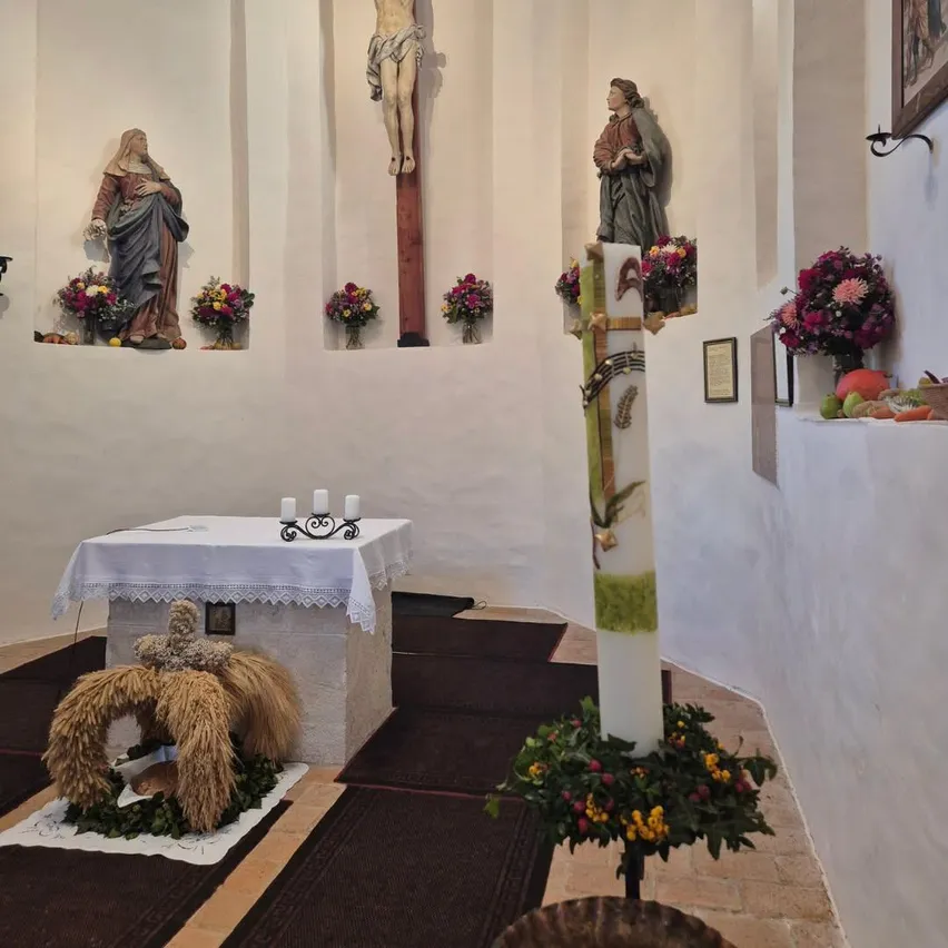 Ein Altar in einer Kapelle mit einem Kreuz, einer Statue von Jesus und einer Statue von Maria.