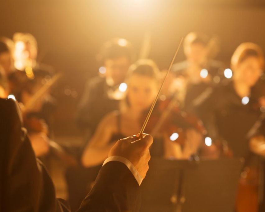 Bild enthält, Indoors, Baton, Stick, Music, Musical Instrument, Musician, Performer, Person, Orchestra, Face